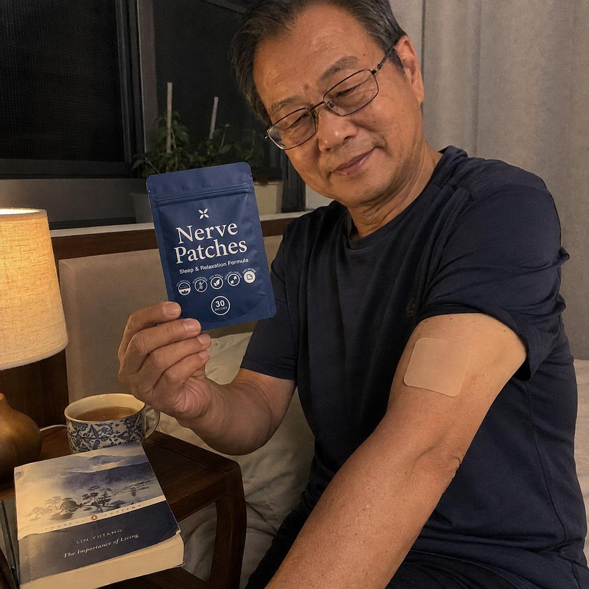A man wearing glasses and a navy blue t-shirt holds up a blue pouch of 'Nerve Patches' while showing a beige nerve patch applied to his upper arm. The setting is a cozy indoor environment with a lit table lamp, a book, and a cup on a wooden side table.